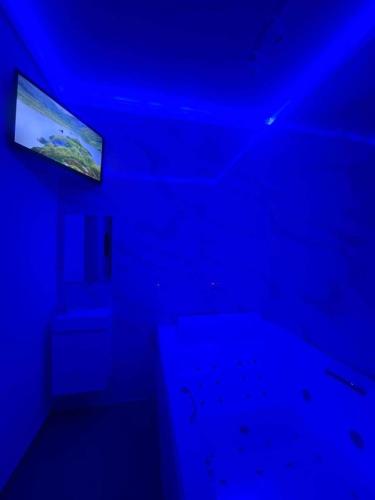 een donkere kamer met een blauw plafond en een televisie bij La Suite Liege in Seraing