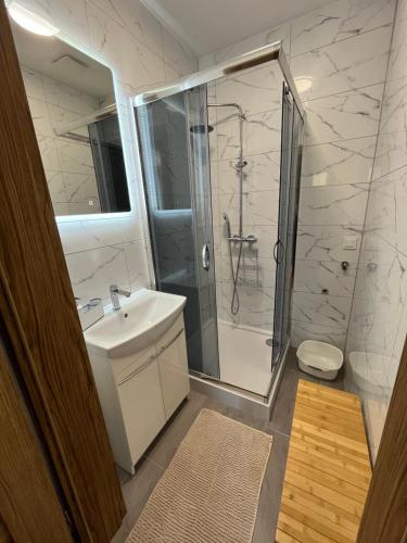 biała łazienka z prysznicem i umywalką w obiekcie Osada Górski Potok Radków w mieście Radków