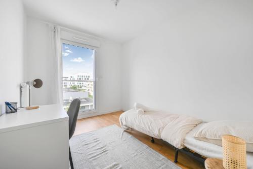 een witte kamer met een bed en een raam bij Appartement Chic au Coeur de Massy in Massy
