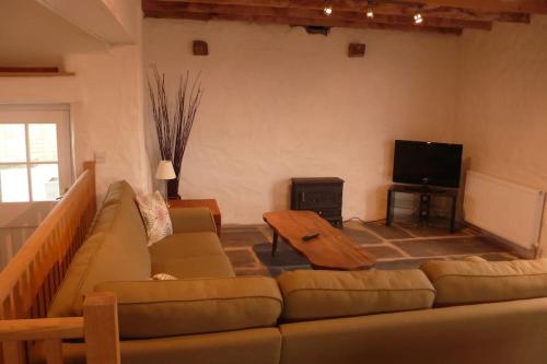 a living room with a couch and a flat screen tv at The Barn at Kingston, Beautiful converted barn in tranquil countryside in Pembroke