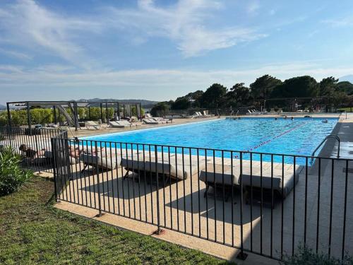 une grande piscine avec des chaises et une clôture dans l'établissement Villa cosy, Porto-vecchio 150m mer, à Porto-Vecchio