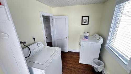 a white laundry room with a washer and dryer at Victoria Cottage in Twillingate