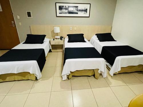 a hotel room with three beds and a table at Hotel Maione in Goiânia