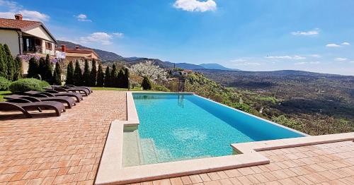 a swimming pool with chairs next to a house at Home Andrea with infinity salty pool in Roč