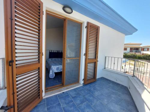a balcony with wooden doors and a bed at cala di seta in Calasetta