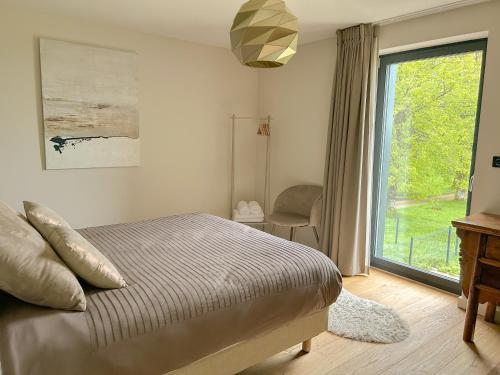 - une chambre avec un lit et une grande fenêtre dans l'établissement Villa de montagne avec piscine intérieure chauffée, à Bellefosse