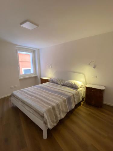 a white bedroom with a bed and a window at Appartamento al Gallo con terrazzo in Arco