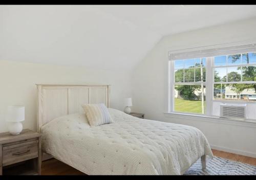 a white bedroom with a bed and a window at Seaside Serenity, Your Pine Point Beach Paradise in Scarborough