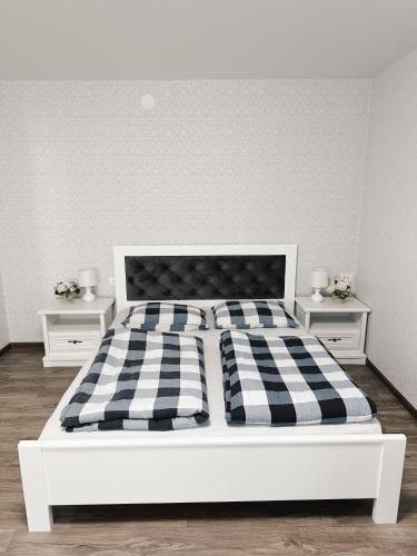 białe łóżko z czarno-białym kocem szachowym w obiekcie Чудесная квартира в изюминке города Берегово w mieście Berehowo