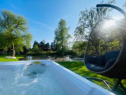 a hot tub with a chair in front of a pond at The Barn cottage with hot tub overlooking the lake in Ringmer