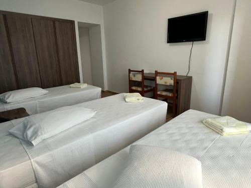 a hotel room with two beds and a flat screen tv at Hotel Quatro Estações in Guarapari
