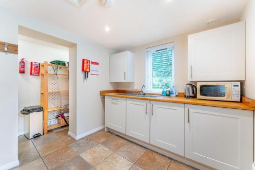 a kitchen with white cabinets and a microwave at Carr Crag Pavilion in Little Langdale
