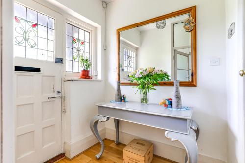 een kamer met een tafel, een spiegel en een deur bij Wisteria Apartment in Mill Hill