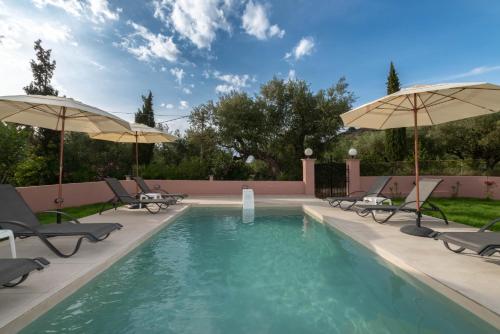 a swimming pool with chairs and umbrellas at Afrodite's Oasis Villa by "elite" in Akrotiri