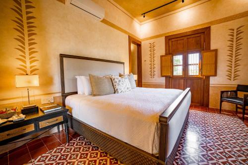 a bedroom with a bed and a desk and a window at Hacienda San Antonio Hool in Mérida