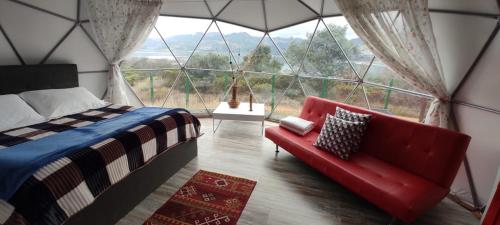 a bedroom with a bed and a couch in front of a window at Hospedaje Mafer in Guatavita