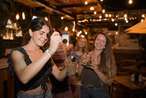 a group of women standing in a bar holding drinks at Che Zipolite Hostel & Beach Club in Zipolite