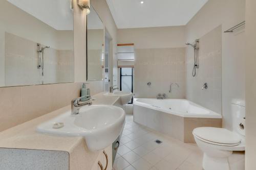 a bathroom with a sink and a tub and a toilet at Marlin Lodge in Tangalooma