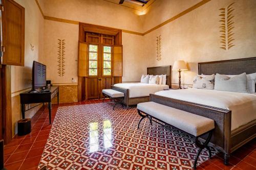 a hotel room with two beds and a television at Hacienda San Antonio Hool in Mérida