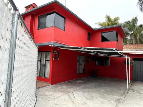 a red house with a white fence in front of it at Cómodas y espaciosas Habitaciones para viajeros por trabajo o vacaciones in Tultitlán