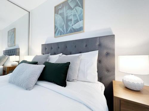 Apartment on Regent في ملبورن: غرفة نوم بسرير ابيض ومخدات خضراء وبيضاء