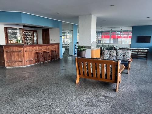 un vestíbulo con un banco y un bar en un edificio en Hotel Quatro Estações, en Guarapari