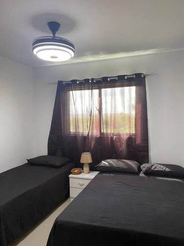 a bedroom with two beds and a lamp and a window at Luxury Penthouse Santo Domingo W in Santo Domingo