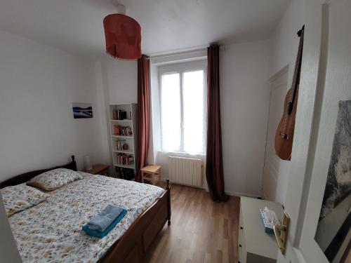 a bedroom with a bed and a window with a guitar at Petite maison proche mer - Flamanville in Flamanville