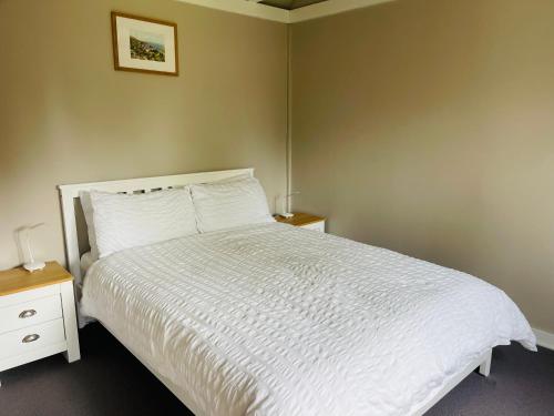 a bedroom with a white bed with two night stands and two lamps at The Barn cottage with hot tub overlooking the lake in Ringmer
