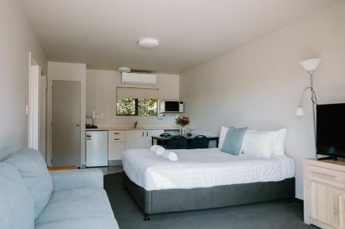 a bedroom with a large bed and a kitchen at Amber Court Motel Nelson in Nelson