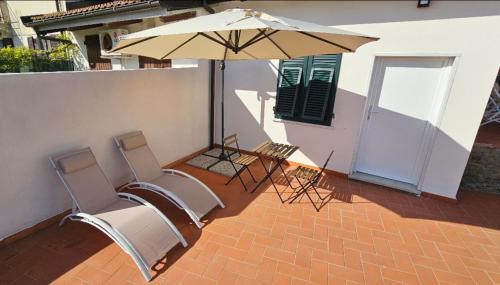 a patio with a table and chairs and an umbrella at Alveari e Nidi in Ameglia