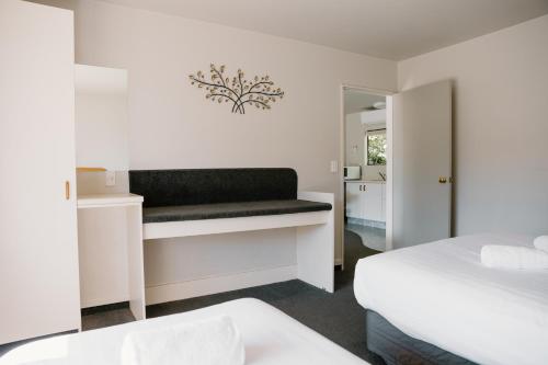 a bedroom with two beds and a bench at Amber Court Motel Nelson in Nelson