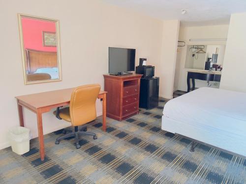 a hotel room with a desk and a bed and a computer at Northgate Inn in Hattiesburg