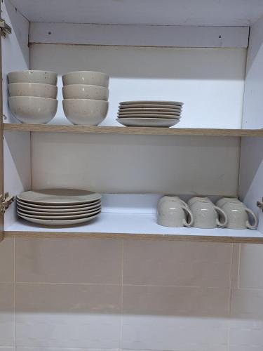 a shelf with plates and cups and dishes on it at Mellow Homes 3 - Own compound in Kitengela 