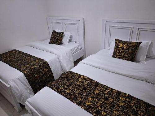 two white beds with black and gold sheets in a room at Mellow Homes 3 - Own compound in Kitengela 