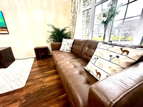 a living room with a brown leather couch with pillows at Coniston Green Holiday Home in Wetherby