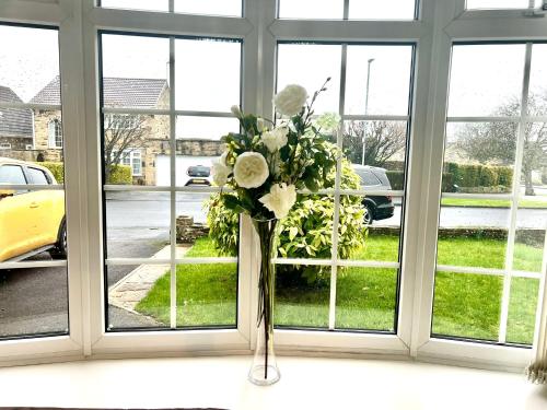 a vase filled with white flowers in a window at Coniston Green Holiday Home in Wetherby