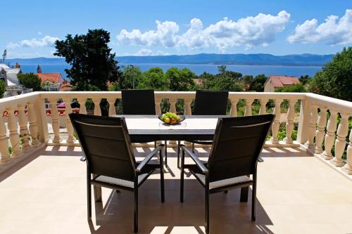 een tafel en stoelen op een balkon met uitzicht bij Apartments Šemper - HEATED POOL in Bol
