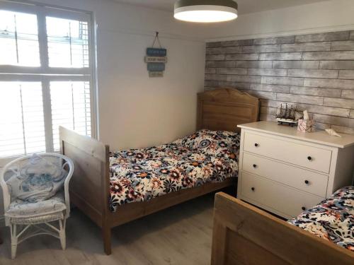 a bedroom with a bed and a dresser and a chair at Iris Cottage in Whitstable