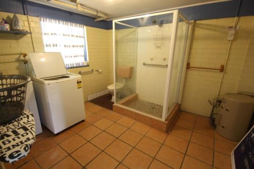 a bathroom with a shower and a white refrigerator at The Castle at Hat Head in Hat Head