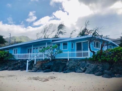 a blue house on the beach with rocks at Moeʻuhane Kai Beach Front Home in Hauula