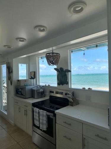 a kitchen with a view of the ocean through a window at Moeʻuhane Kai Beach Front Home in Hauula
