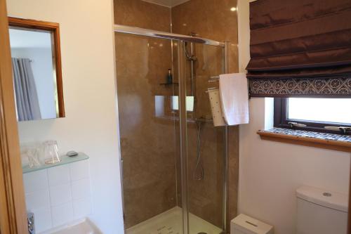a shower with a glass door in a bathroom at Otter Cottage in Manish