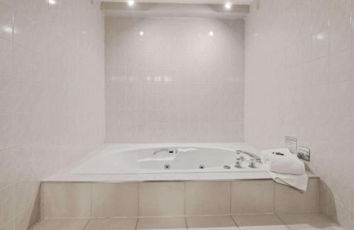 a white bathroom with a bath tub in it at Best Western Plus Cairn Croft Hotel in Niagara Falls