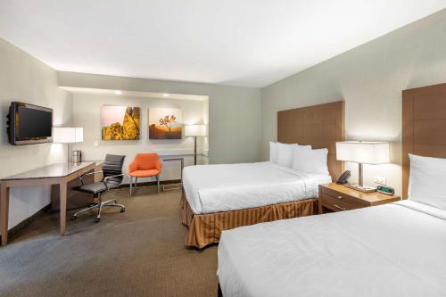 a hotel room with two beds and a desk at Best Western Inn at Palm Springs in Palm Springs