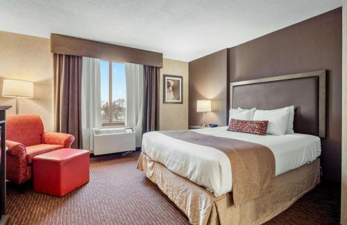 a hotel room with a large bed and a chair at Best Western Plus Cairn Croft Hotel in Niagara Falls