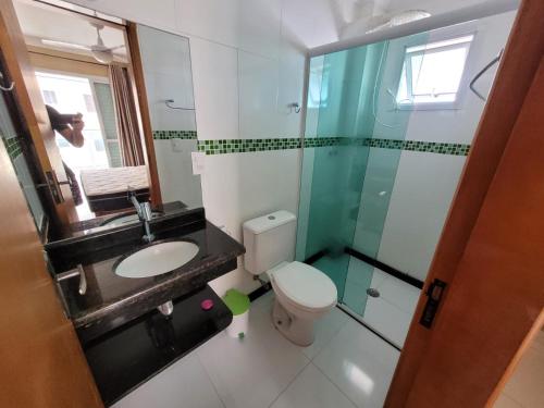 a bathroom with a toilet and a sink and a shower at Apartamento de frente para o mar, 3 quartos in Solemar
