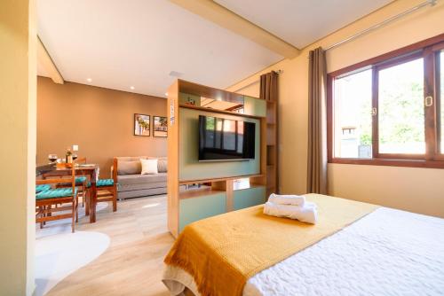 um quarto com uma cama e uma televisão num quarto em Lofts Corujinha Paraty em Paraty