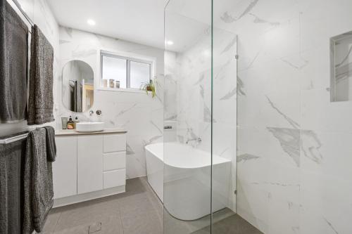 a white bathroom with a shower and a sink at Aloka By Khove in Gold Coast