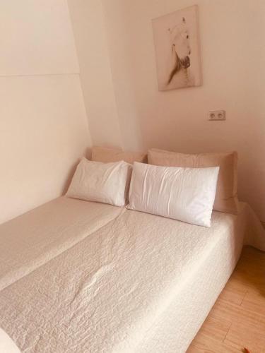 un lit avec des draps blancs et des oreillers dans une chambre dans l'établissement CHEZ MOUNAIM, à Bondy